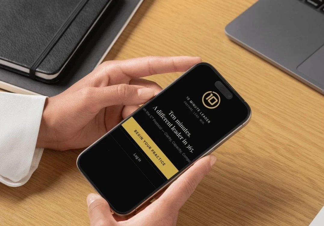 A hand holding a phone showing the 10 Minute Leaders app with a Begin Your Practice button
